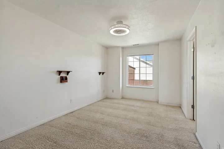 Recessed window with grid pattern, carpeted flooring, and a ceiling-mounted light fixture with a fan