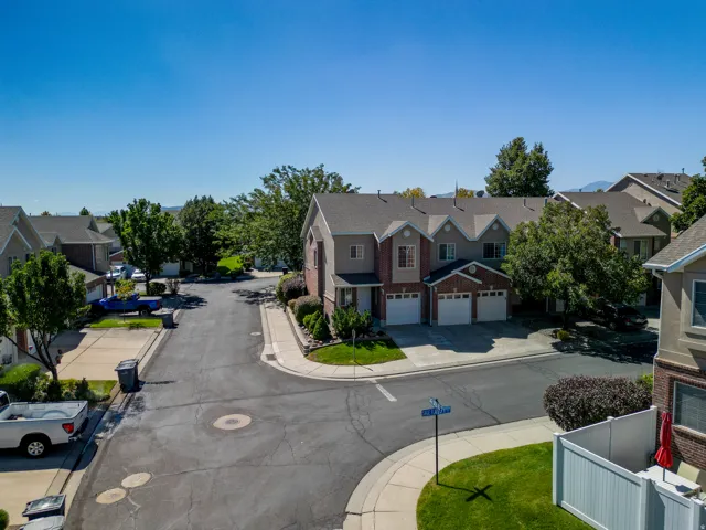 Townhome exterior with a brick and siding facade, multiple garage doors, and mature landscaping