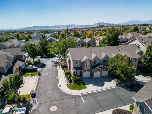 Townhome complex featuring brick and siding exteriors, multi-car garages, and mature landscaping