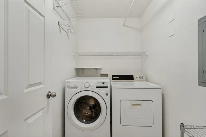 Dedicated laundry area featuring a full-size washer and dryer, wire shelving, and a built-in clothes rod