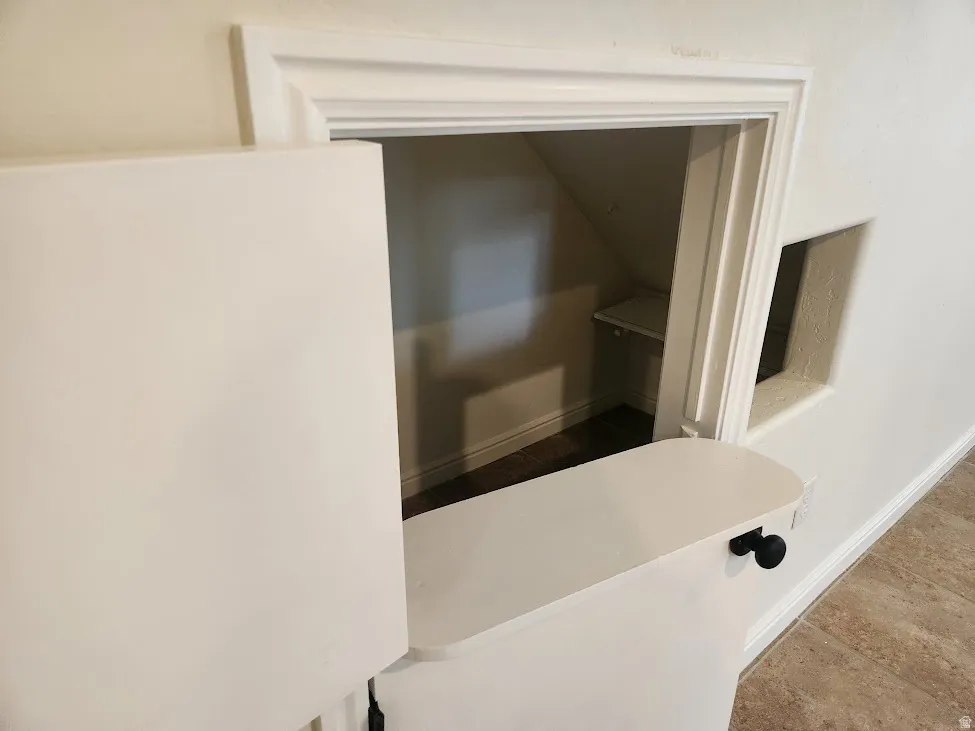 Built-in nook with white trim, interior shelving, and dark wood-finish flooring