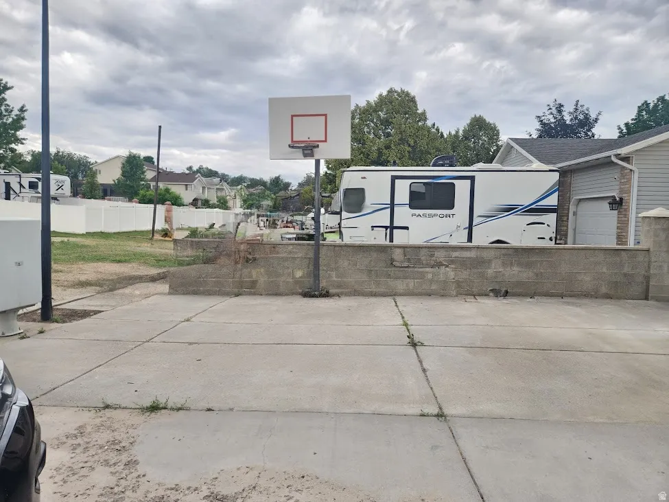 Poured concrete pad with an adjacent block retaining wall and basketball hoop