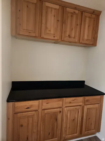Wood-finish cabinetry with multiple drawers and doors, complemented by a dark countertop