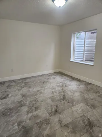 Neutral wall finishes, flush mount ceiling lighting, and a single window with a window well