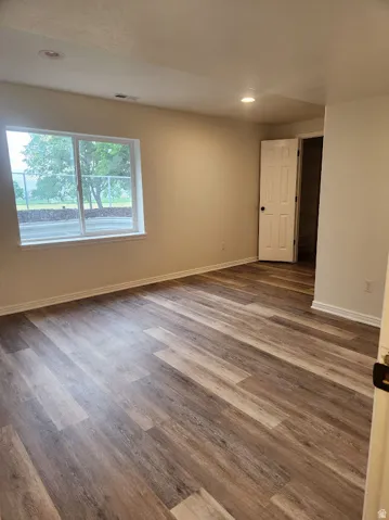 Recessed lighting, wood-finish flooring, white trim, and a window with a neutral wall tone