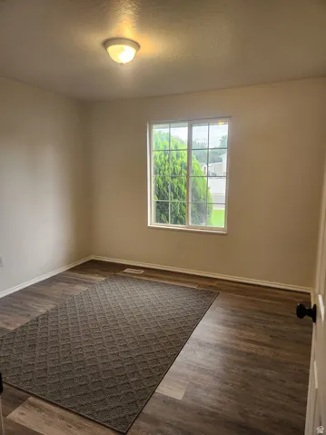 Wood-finish flooring, white trim, and a flush mount ceiling light