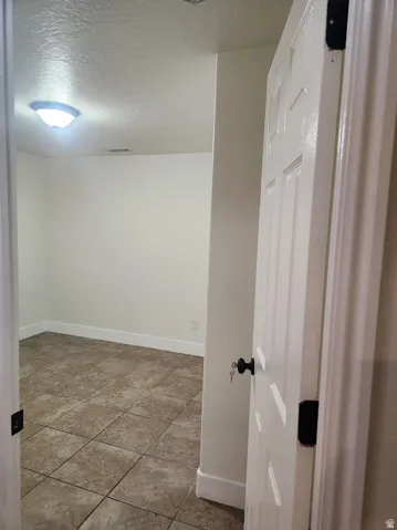 White paneled door with matte black hardware, white walls, and square tile flooring