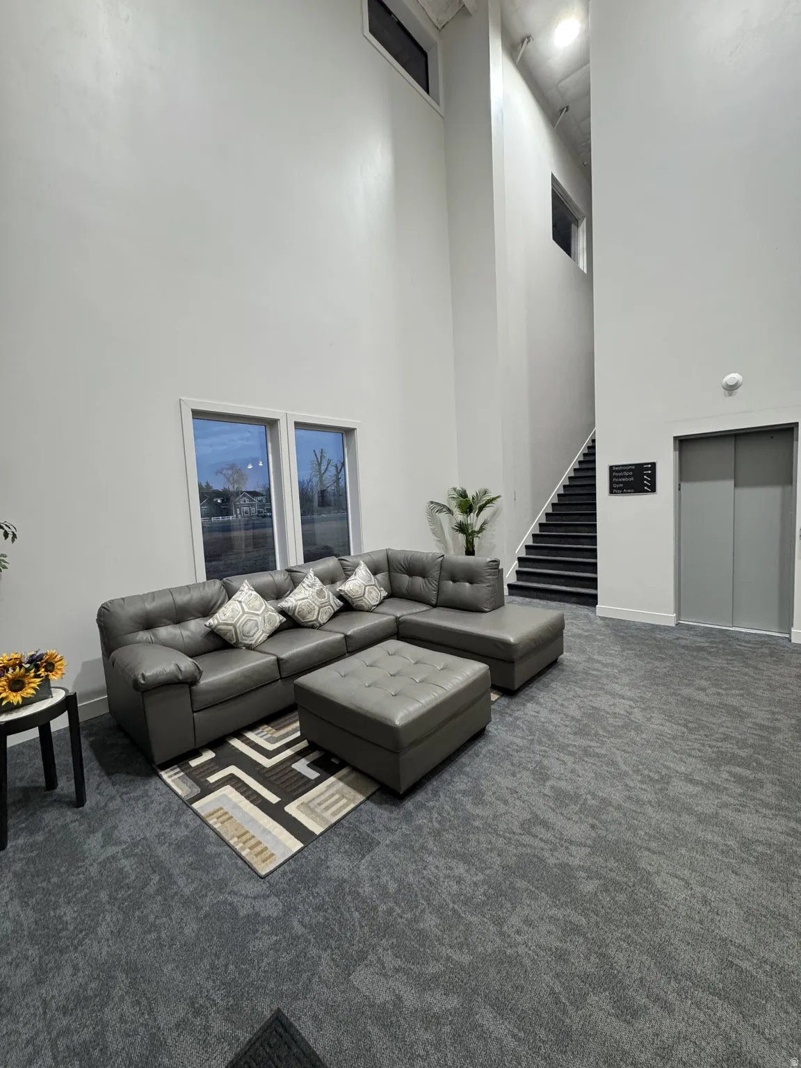 High ceilings with upper windows, integrated staircase with dark treads, and an elevator access