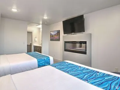 Recessed lighting, built-in electric fireplace, wall-mounted television, and a vanity with dual sinks visible through a doorway