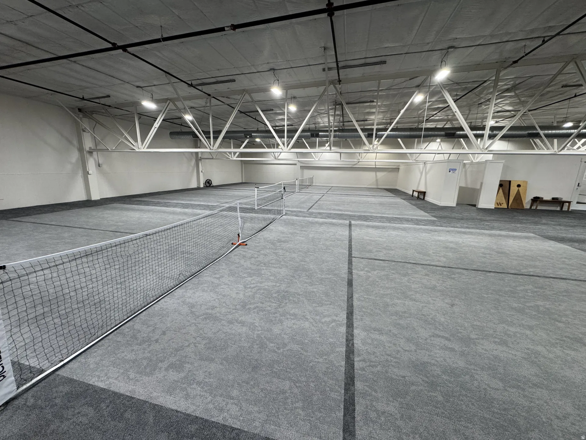 Indoor court space featuring multiple playing areas, high ceilings with exposed trusses, and integrated overhead lighting
