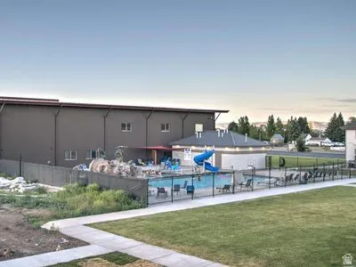 Outdoor pool area featuring a blue waterslide, perimeter fencing, and a surrounding concrete patio