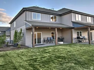 Expansive grass lawn leading to a covered patio with recessed lighting and structural wood-finish posts
