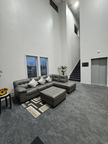 High ceilings with upper windows, integrated staircase with dark treads, and an elevator access