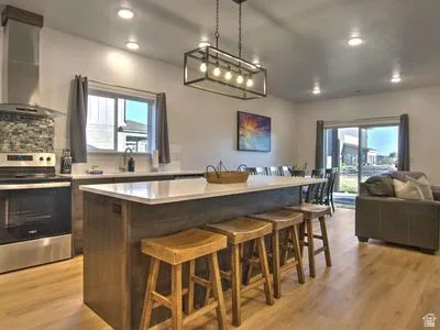 Contemporary kitchen featuring a large island with seating, stainless steel appliances, a tiled backsplash, and recessed lighting