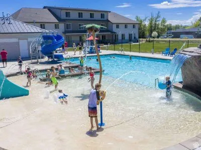 Expansive outdoor pool area featuring a large swimming pool, splash pad, water slide, and rock waterfall feature