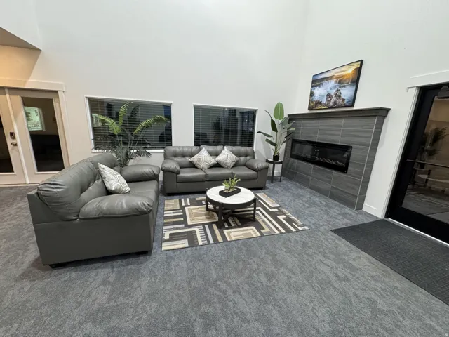 Vaulted ceiling with recessed lighting, linear electric fireplace with tiled surround, multiple windows with blinds, and durable carpeting