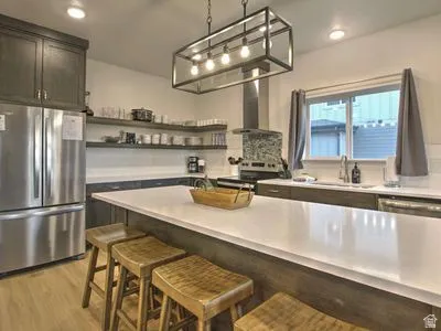 Kitchen featuring stainless steel appliances, open shelving, a center island with countertop seating, and a large window above the sink