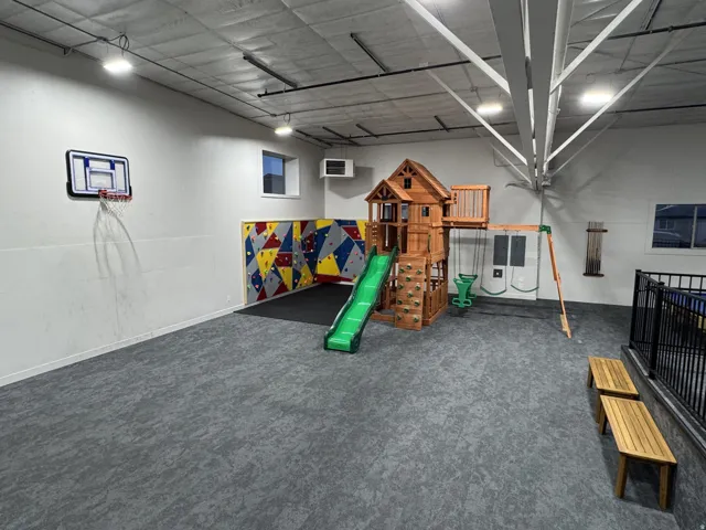 Spacious interior featuring patterned wall-to-wall carpeting, exposed ceiling beams, and recessed lighting