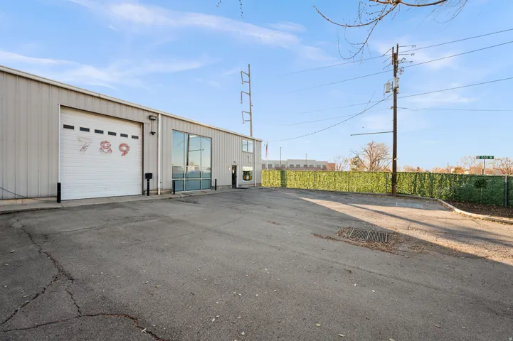 Industrial-style building with a metal exterior, a large roll-up door, expansive glass window panels, and a paved lot