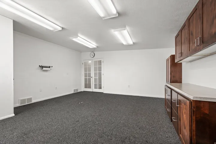 Recessed lighting, wood-finish cabinetry, countertop space, and French doors with glass panes