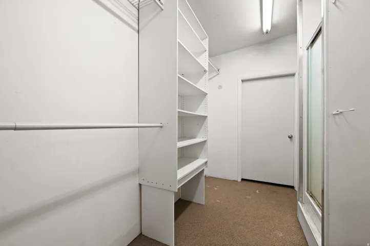 Walk-in closet with built-in shelving, hanging rods, and recessed lighting