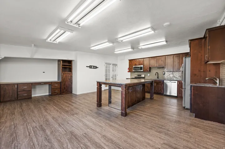 Wood-finish flooring throughout, featuring a kitchen with wood cabinetry, stainless steel appliances, and a tiled backsplash