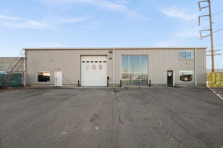 Metal-sided industrial building featuring an overhead door, multiple windows, and exterior stairs