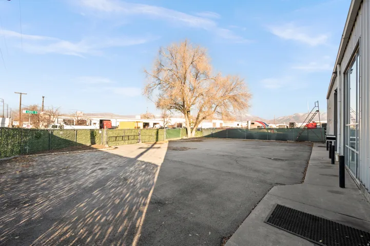 Paved lot with perimeter fencing and a large mature tree
