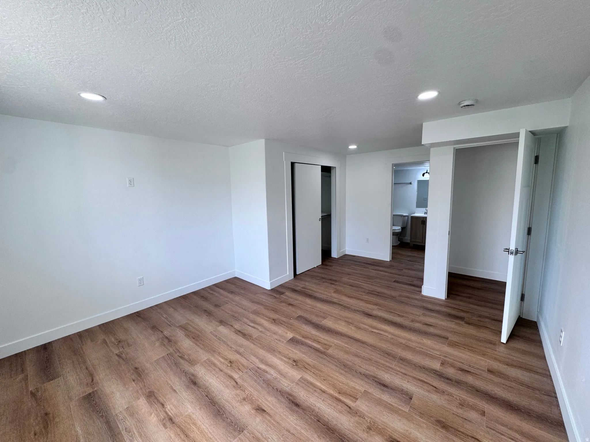Wood-finish flooring, recessed lighting, white walls, and white trim