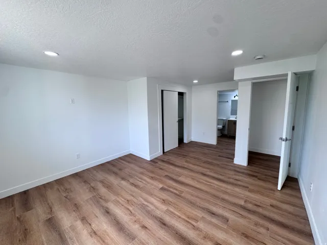 Wood-finish flooring, recessed lighting, white walls, and white trim