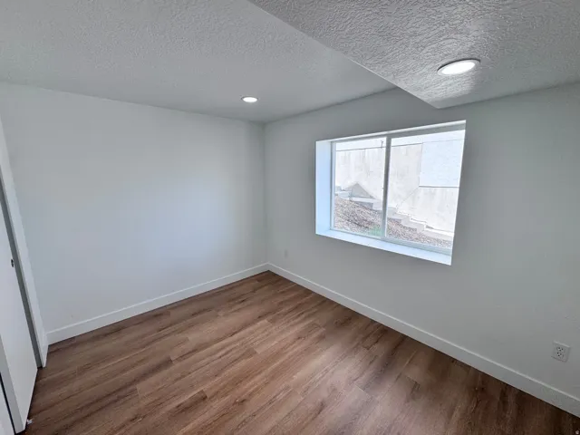 Wood-finish flooring, recessed lighting, base molding, and a window with a white frame