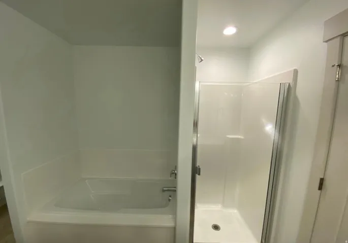 Built-in bathtub with chrome fixtures, enclosed shower with sliding glass door, and recessed lighting