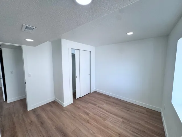 Wood-finish flooring, recessed lighting, white walls, and white sliding closet doors