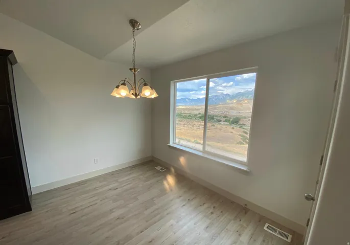Recessed ceiling detail, wood-finish flooring, large window, and wall-mounted lighting fixture