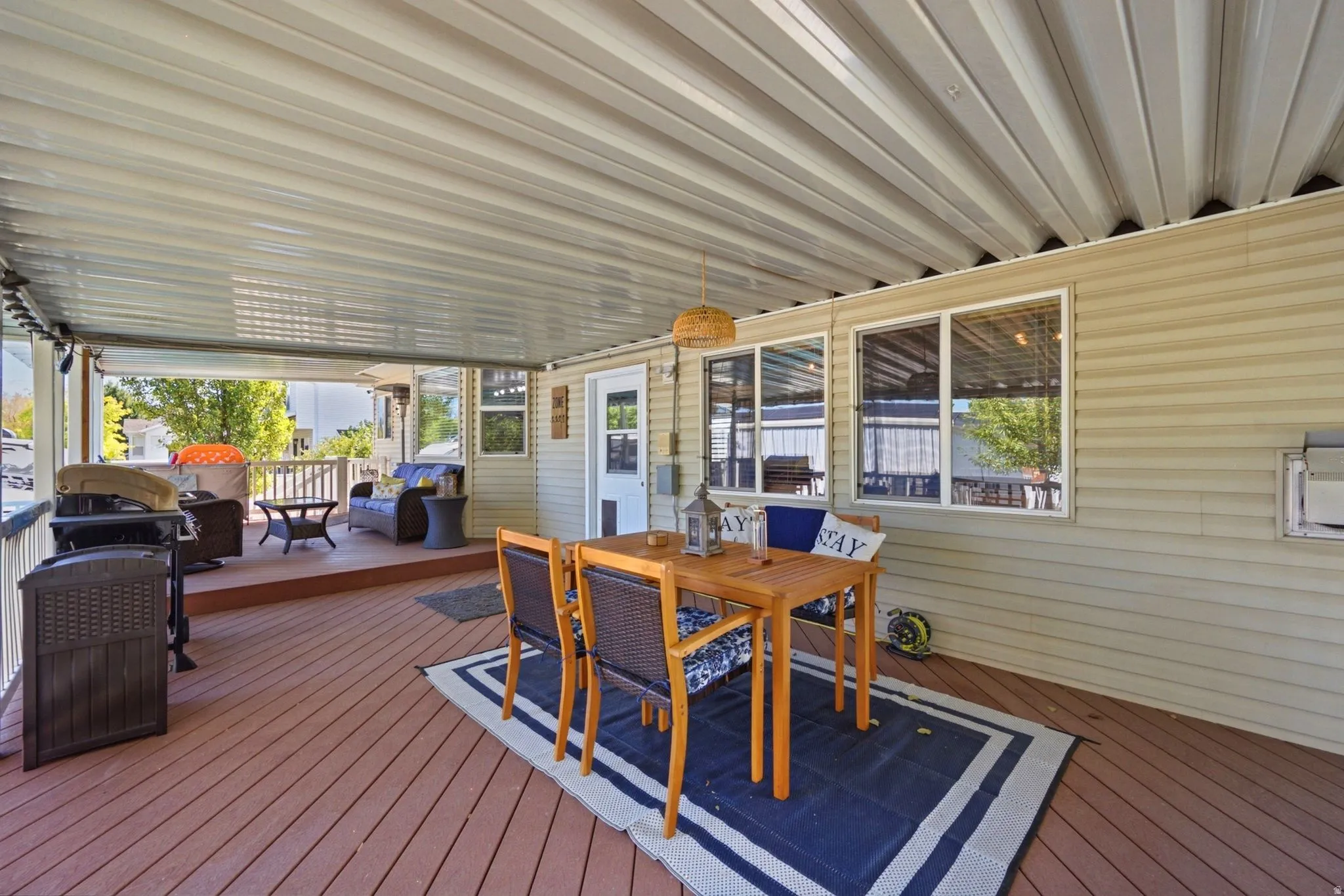 Expansive covered deck featuring wood-finish flooring, a corrugated metal ceiling, and multiple windows along the exterior wall