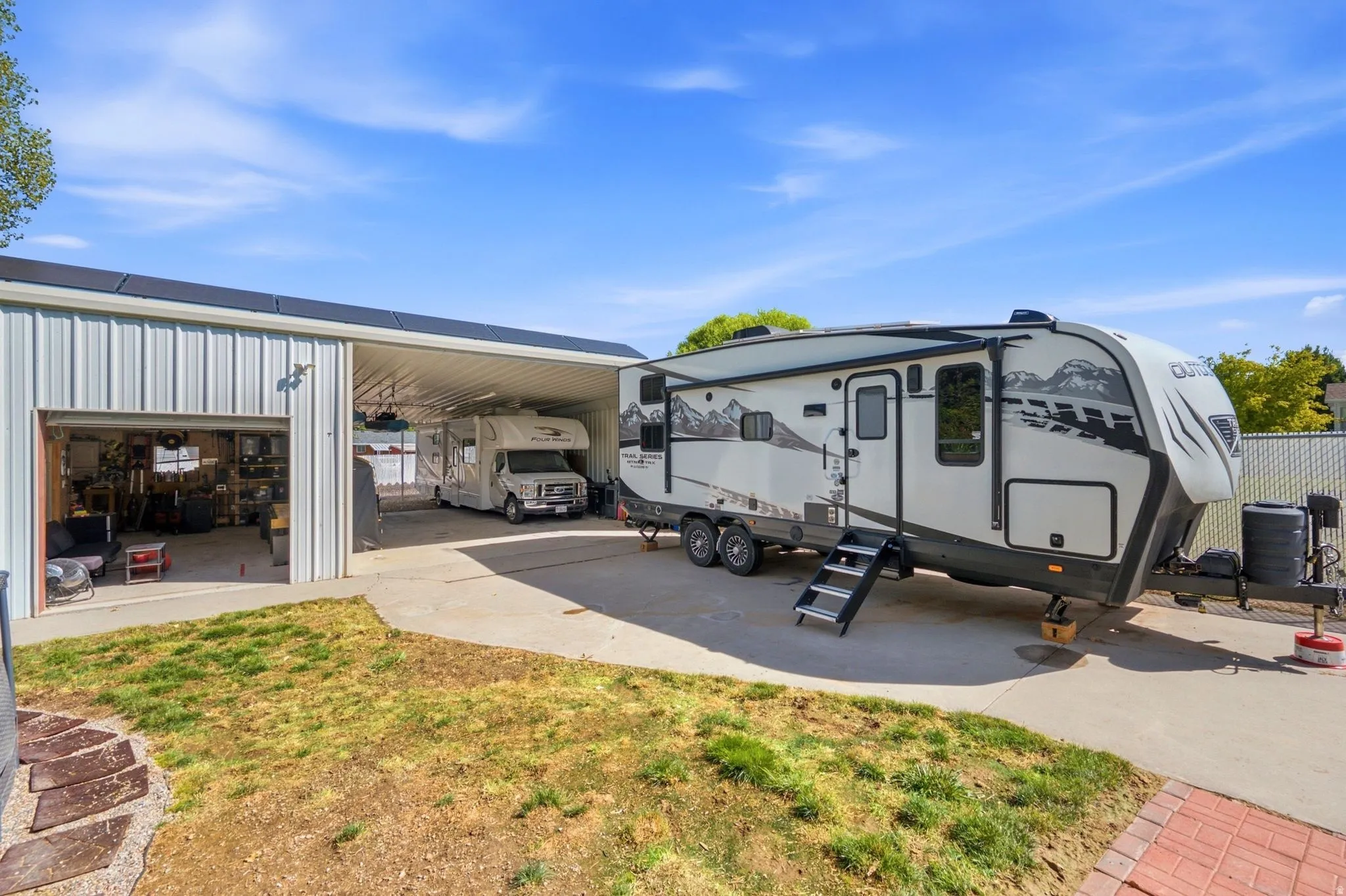 Metal outbuilding with roll-up door, covered concrete parking, and concrete driveway