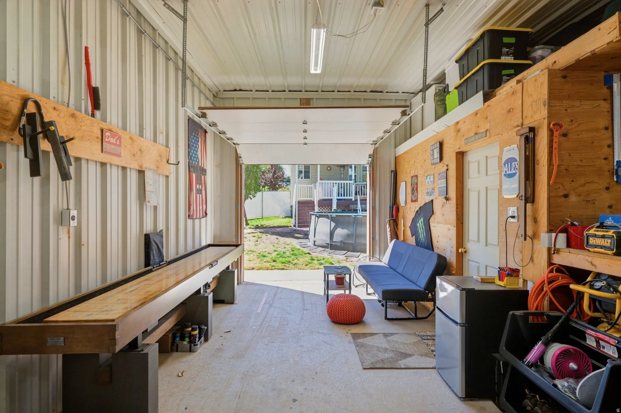 Enclosed structure featuring corrugated metal walls and ceiling, exposed wood paneling, and concrete flooring