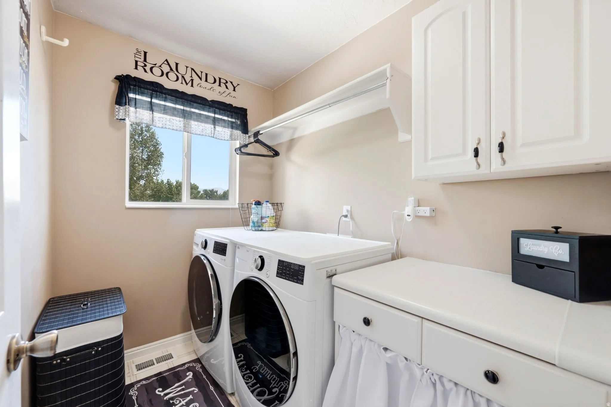 Dedicated laundry room featuring upper cabinetry, a built-in counter, and a window
