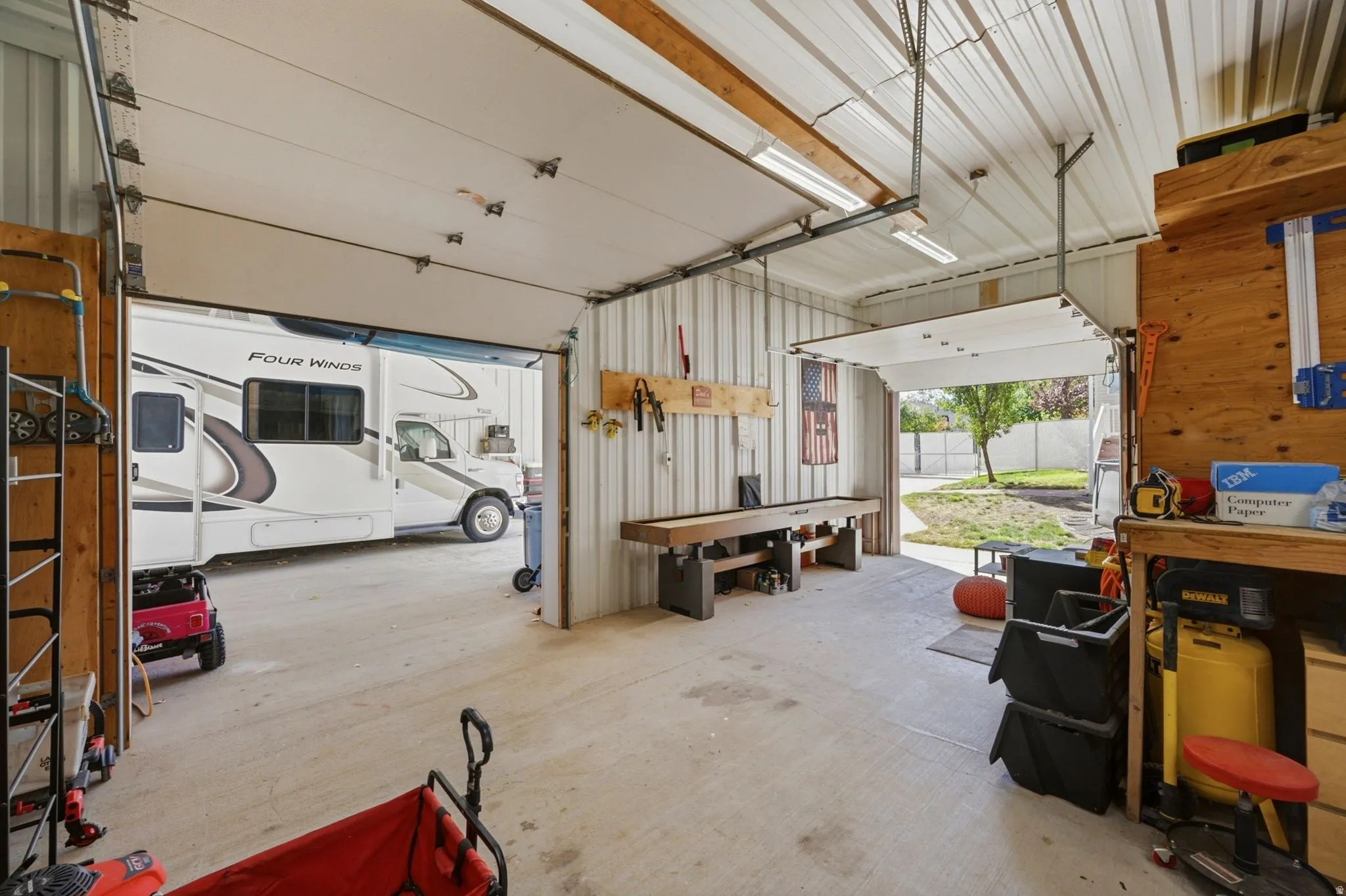Spacious garage with multiple overhead doors, high ceilings, exposed metal framing, and concrete flooring