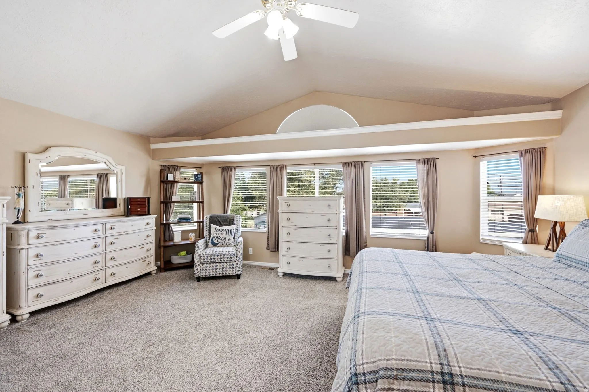 Vaulted ceiling featuring a ceiling fan, carpeted flooring, and multiple windows