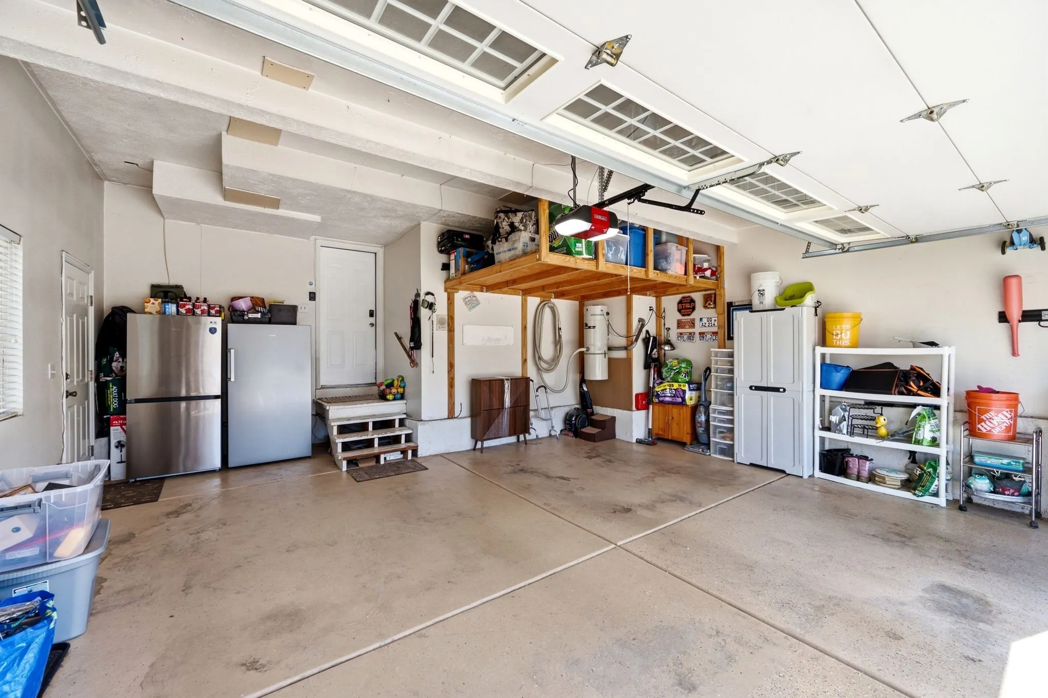 Concrete flooring with expansion joints, overhead garage door with upper window inserts, and built-in wood shelving