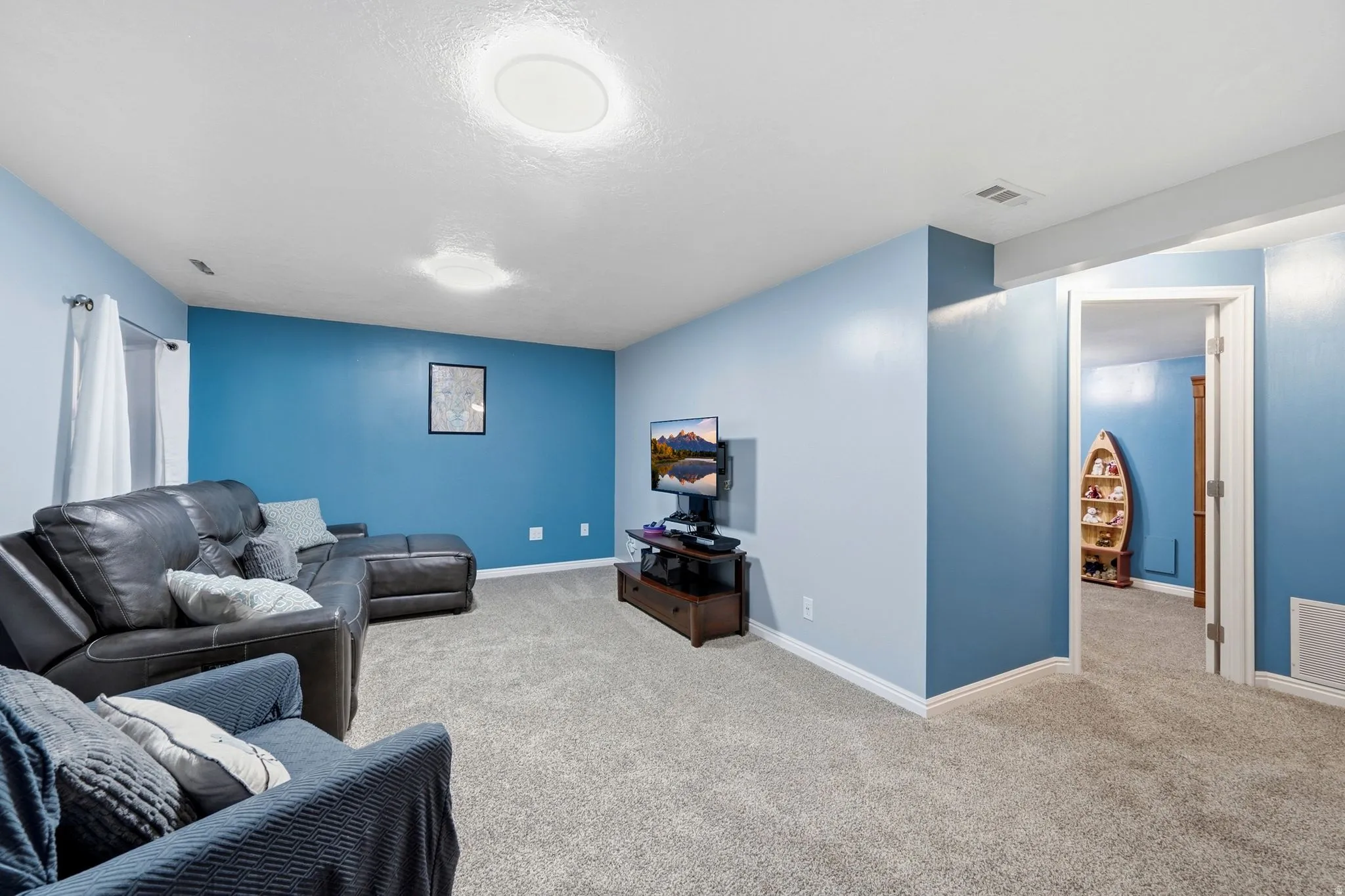 Spacious room featuring light blue and deep blue accent walls, plush carpet flooring, and recessed ceiling lighting