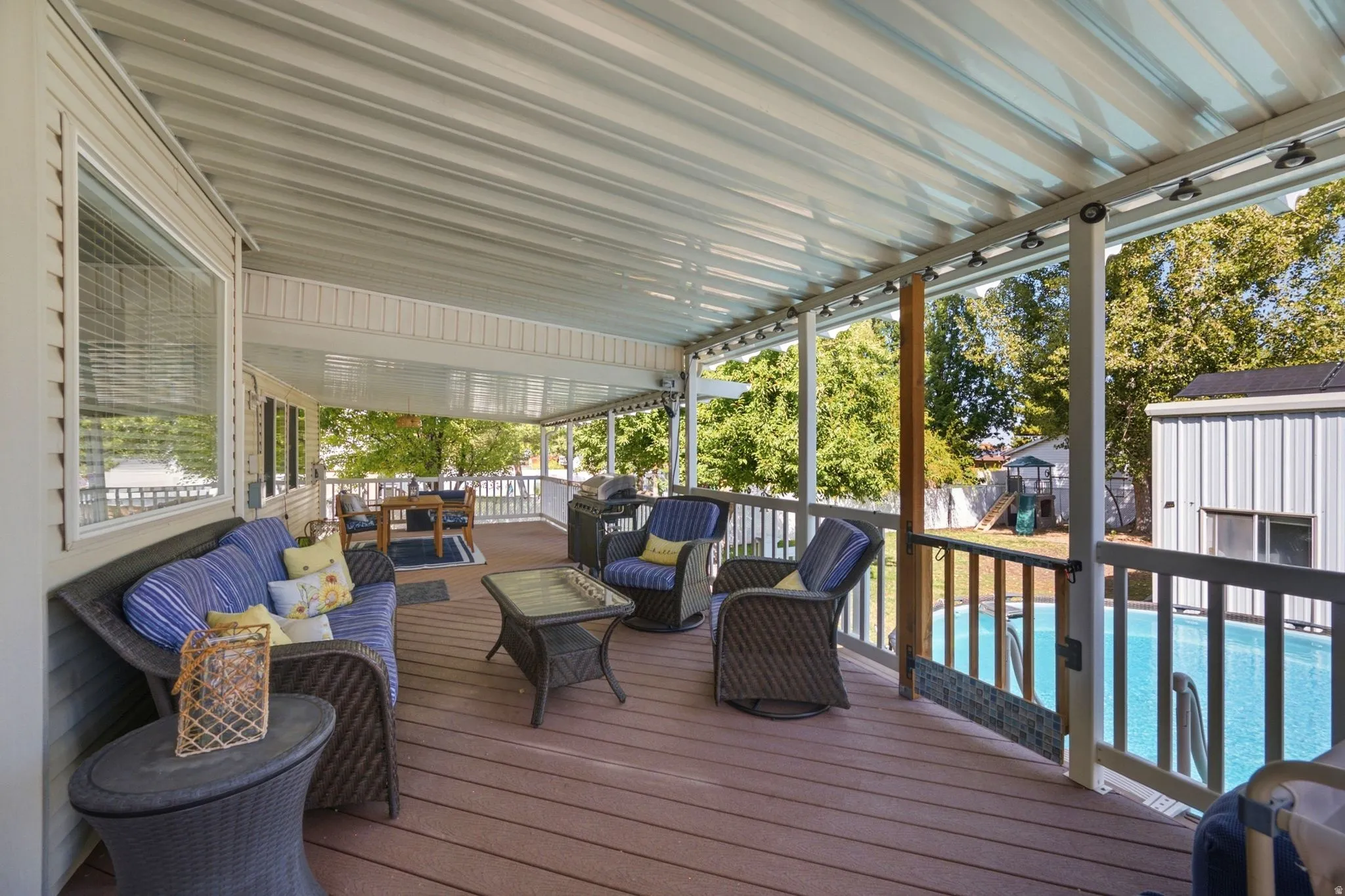 Expansive covered deck featuring composite decking, recessed lighting, and a railing system overlooking an above-ground pool