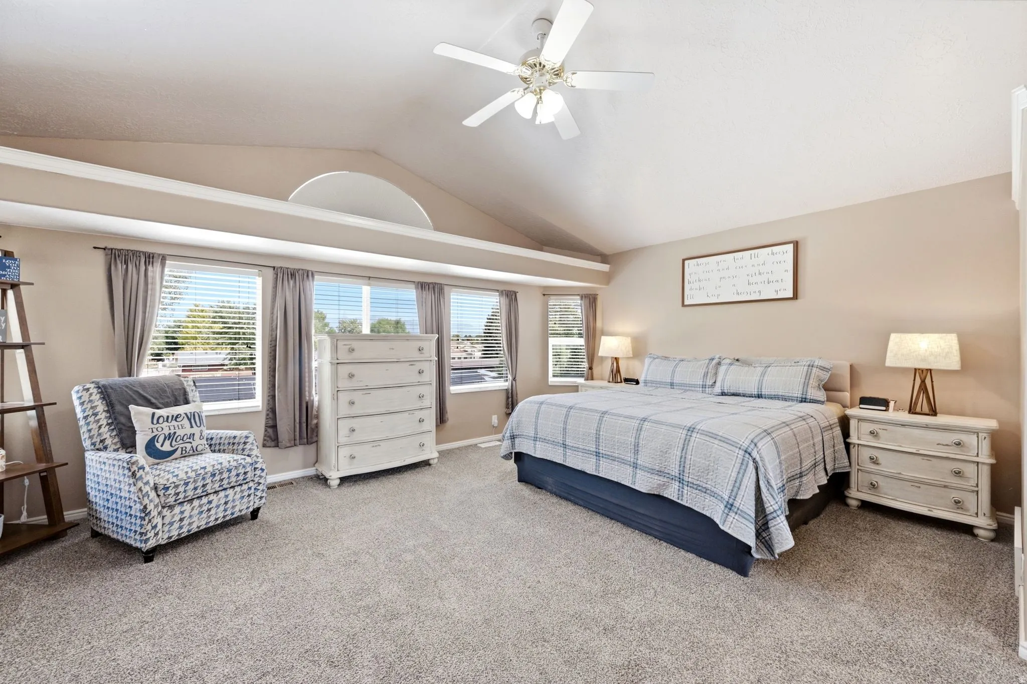 Vaulted ceilings with a ceiling fan, multiple windows with blinds, and neutral-toned wall paint