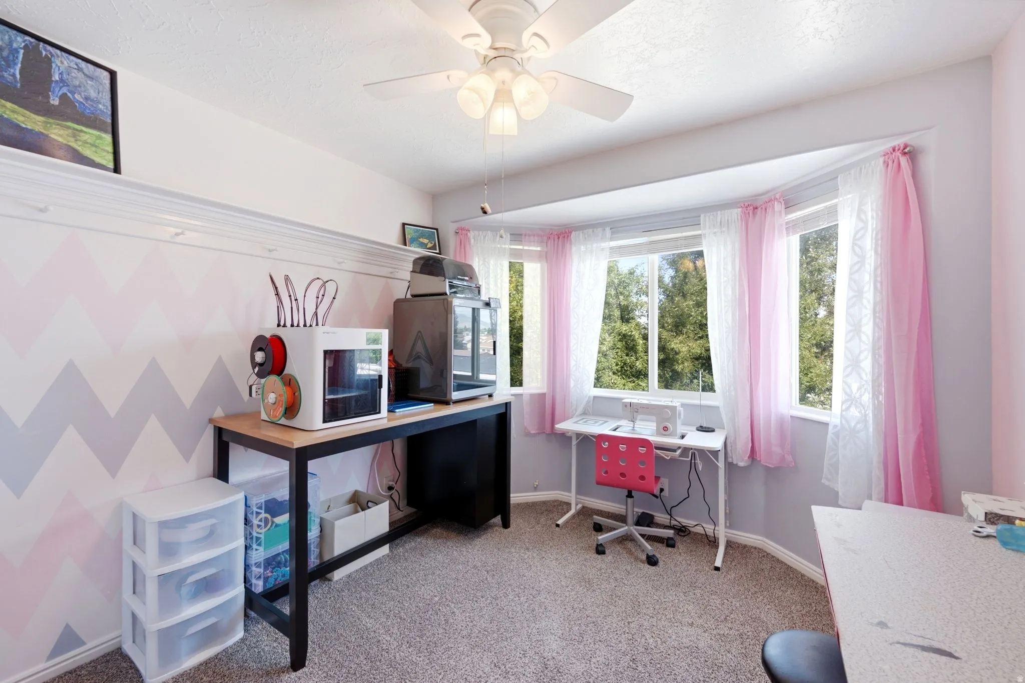 Bay window, textured carpeting, ceiling fan, and crown molding