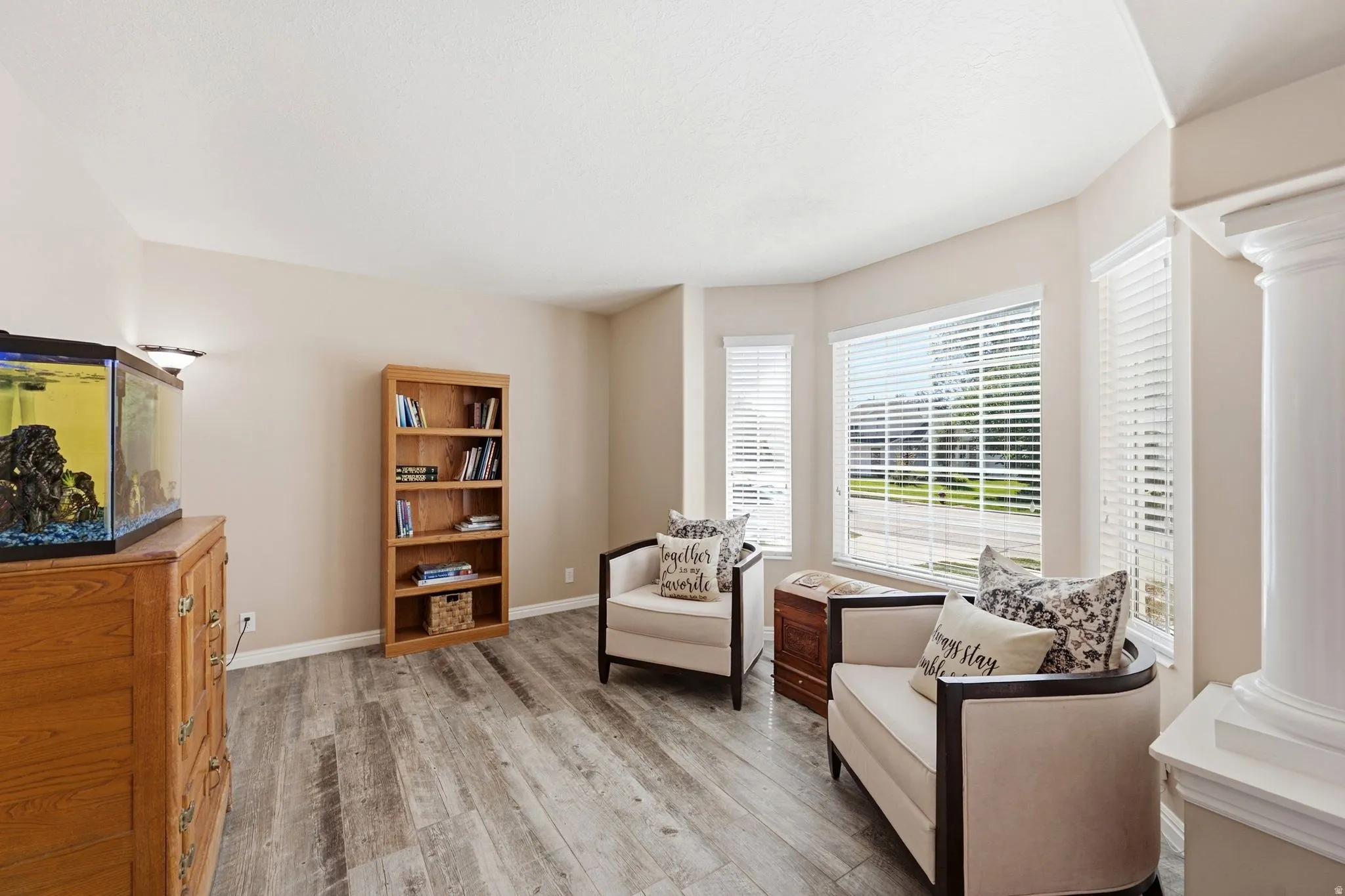 Bay window with multiple windows, wood-finish flooring, built-in shelving, and neutral wall tones