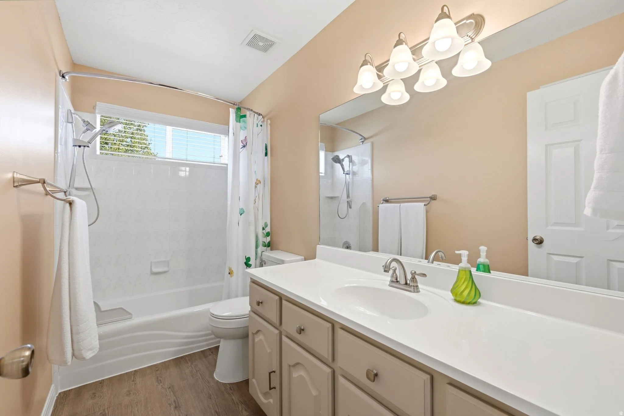 Bathroom featuring a white vanity countertop, undermount sink, dual-handle chrome faucet, and a large mirror with a vanity light fixture