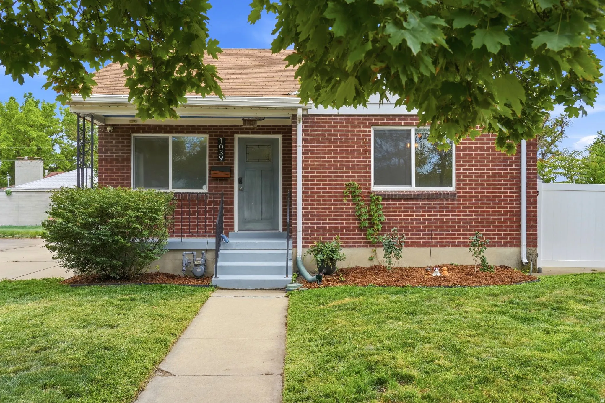 Brick exterior with white trim, gray entry door, and a manicured lawn