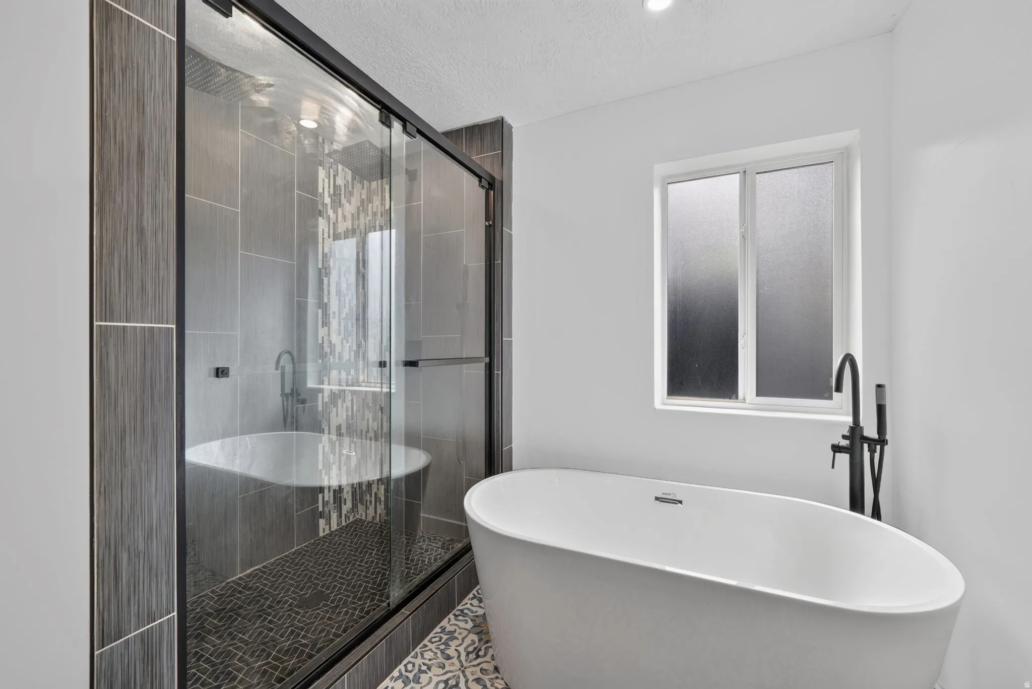 Freestanding soaking tub with a matte black floor-mounted faucet