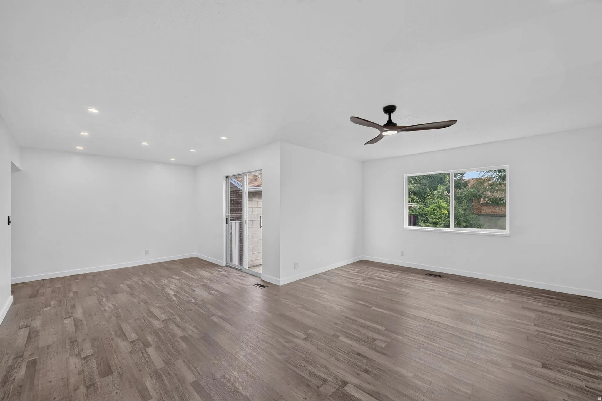 Wood-finish flooring, recessed lighting, ceiling fan, and sliding glass door